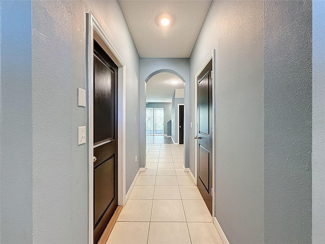 hall featuring light tile patterned flooring and a textured ceiling