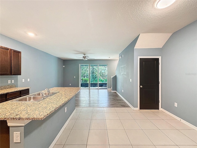 kitchen featuring a textured ceiling, ceiling fan, sink, light hardwood / wood-style flooring, and an island with sink