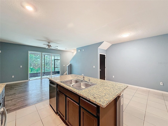 kitchen with light wood-type flooring, a textured ceiling, a kitchen island with sink, sink, and dishwasher