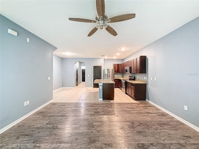 kitchen with a center island, light hardwood / wood-style flooring, ceiling fan, dark brown cabinetry, and stainless steel appliances