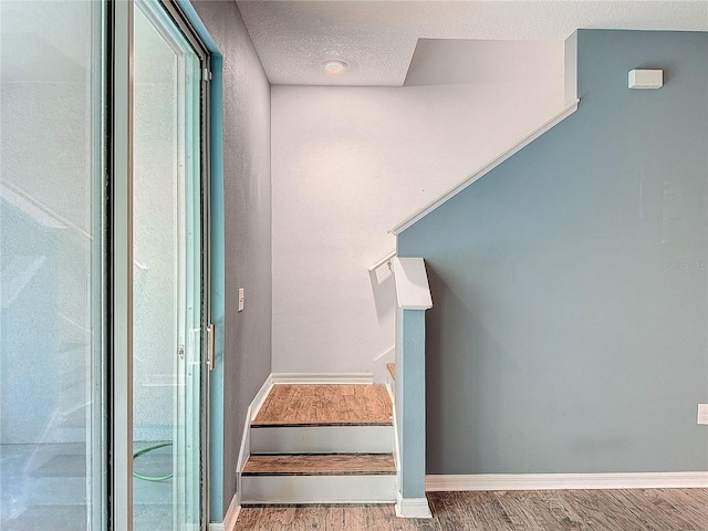 stairway featuring a textured ceiling and hardwood / wood-style flooring