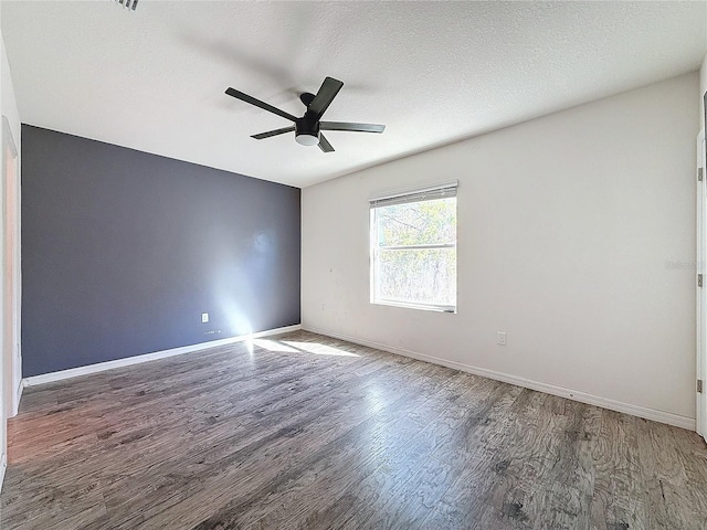 spare room with a textured ceiling, dark hardwood / wood-style flooring, and ceiling fan