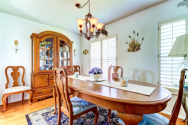 dining area with a textured ceiling, a chandelier, wood-type flooring, and plenty of natural light