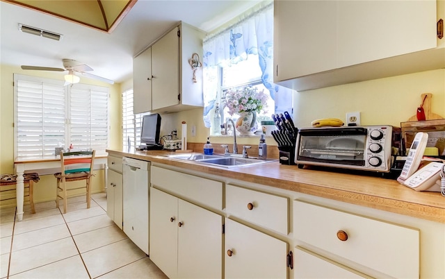 kitchen with white dishwasher, sink, ceiling fan, light tile patterned flooring, and white cabinetry