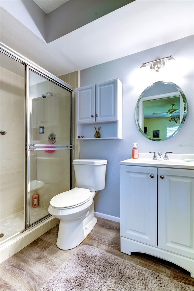 bathroom featuring toilet, vanity, hardwood / wood-style floors, and a shower with shower door