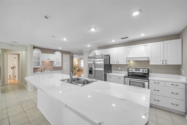 kitchen with white cabinetry, appliances with stainless steel finishes, sink, and a large island with sink