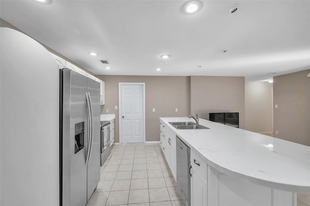 kitchen with white cabinets, sink, light tile patterned floors, and stainless steel appliances