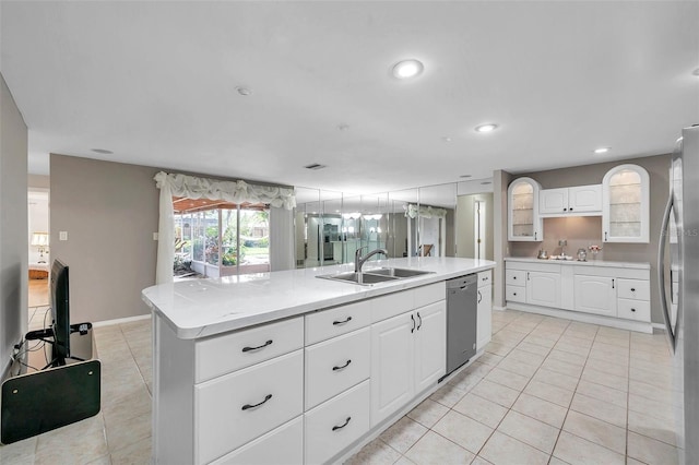 kitchen with appliances with stainless steel finishes, light tile patterned floors, sink, an island with sink, and white cabinets