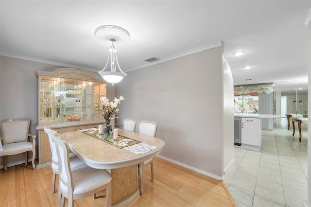 dining area featuring light hardwood / wood-style floors and crown molding