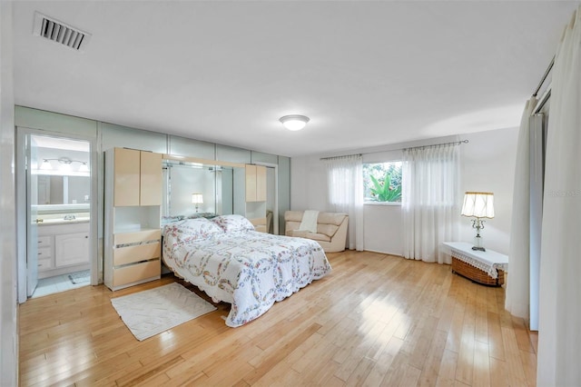 bedroom with ensuite bath and light hardwood / wood-style floors