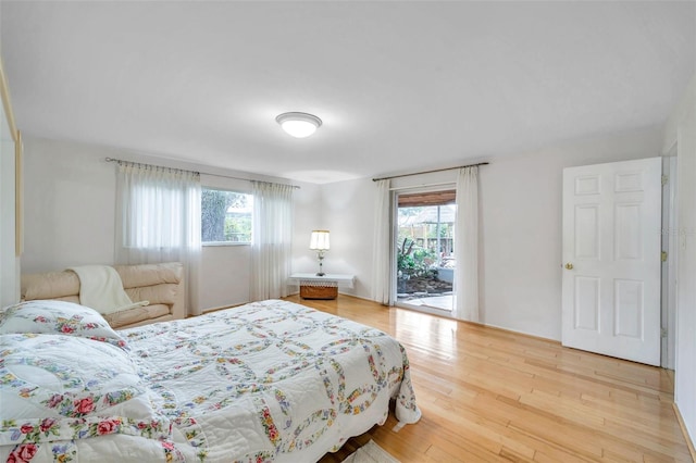 bedroom with multiple windows, hardwood / wood-style flooring, and access to exterior