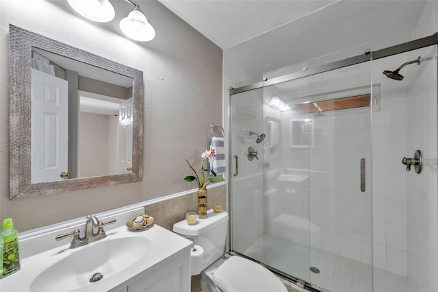 bathroom with a shower with door, vanity, and toilet