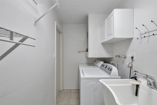 clothes washing area with washer and clothes dryer, cabinets, sink, and light tile patterned flooring