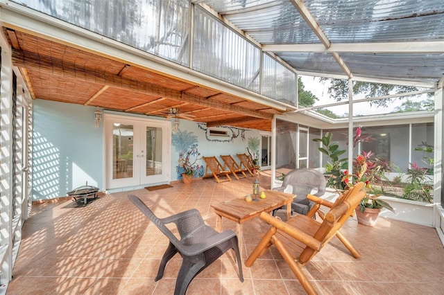 sunroom / solarium featuring a wall unit AC, french doors, a wealth of natural light, and lofted ceiling