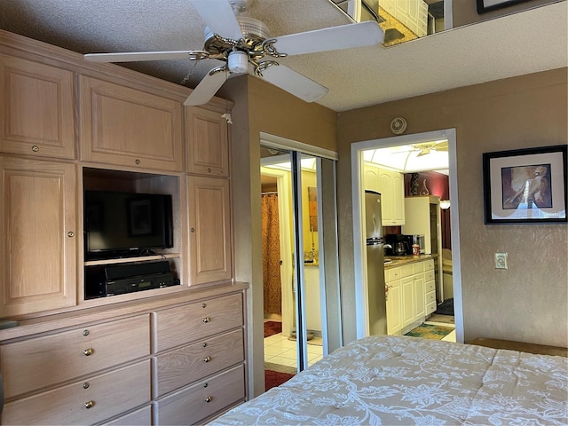 bedroom with ensuite bathroom, a textured ceiling, ceiling fan, and stainless steel fridge