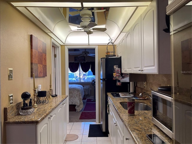 kitchen with stainless steel appliances, stone countertops, sink, light tile patterned floors, and white cabinets