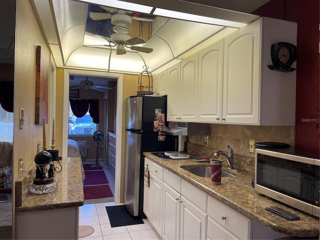 kitchen featuring sink, appliances with stainless steel finishes, light tile patterned floors, stone counters, and white cabinets