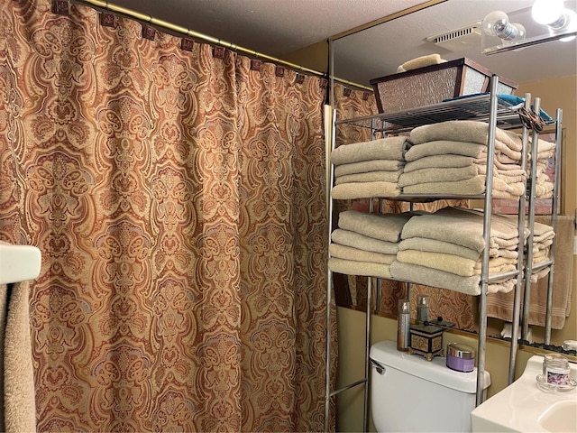 bathroom with toilet and a textured ceiling