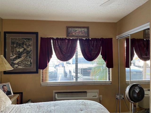 bedroom featuring a wall unit AC, a textured ceiling, and a closet