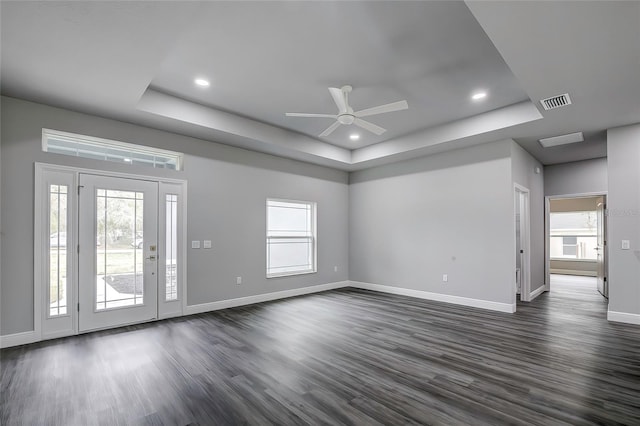 interior space with a tray ceiling, dark hardwood / wood-style flooring, and plenty of natural light