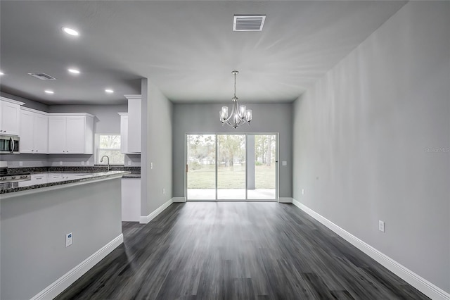 kitchen featuring white cabinets, dark hardwood / wood-style floors, dark stone counters, and a notable chandelier