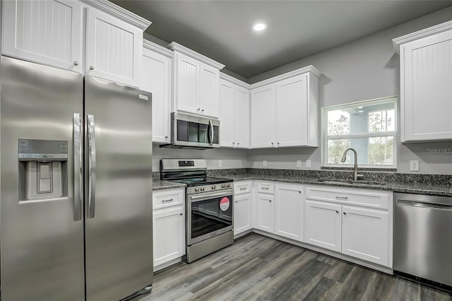 kitchen featuring sink, dark wood-type flooring, dark stone countertops, white cabinets, and appliances with stainless steel finishes