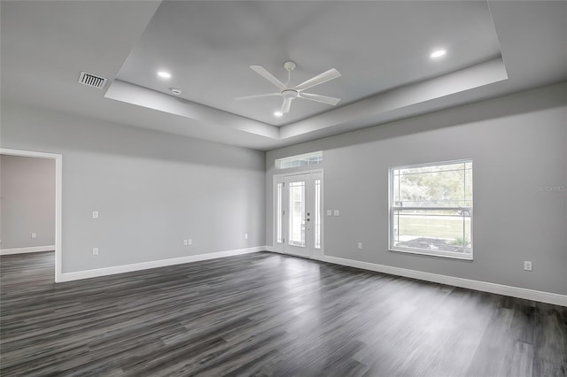 spare room with ceiling fan, a raised ceiling, and dark wood-type flooring