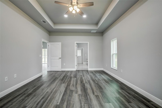 unfurnished room featuring dark hardwood / wood-style flooring, a raised ceiling, and ceiling fan