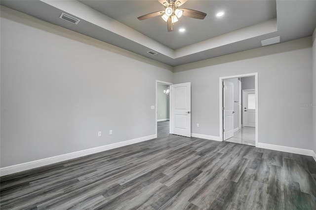 unfurnished bedroom featuring hardwood / wood-style flooring, ceiling fan, and a tray ceiling