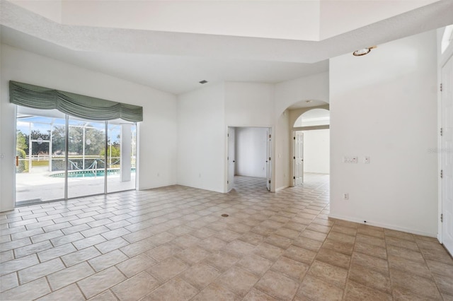 unfurnished room with a towering ceiling and light tile patterned floors