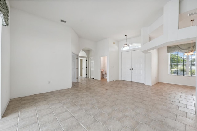 unfurnished room with a towering ceiling and an inviting chandelier