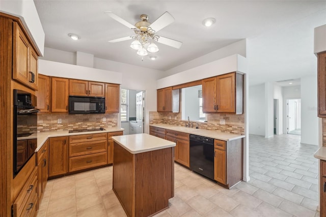 kitchen with a center island, black appliances, sink, ceiling fan, and backsplash