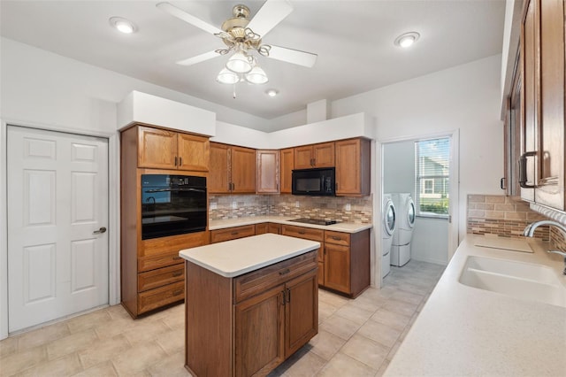 kitchen featuring separate washer and dryer, a center island, black appliances, sink, and ceiling fan