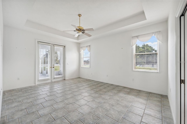 spare room with plenty of natural light, ceiling fan, and a tray ceiling