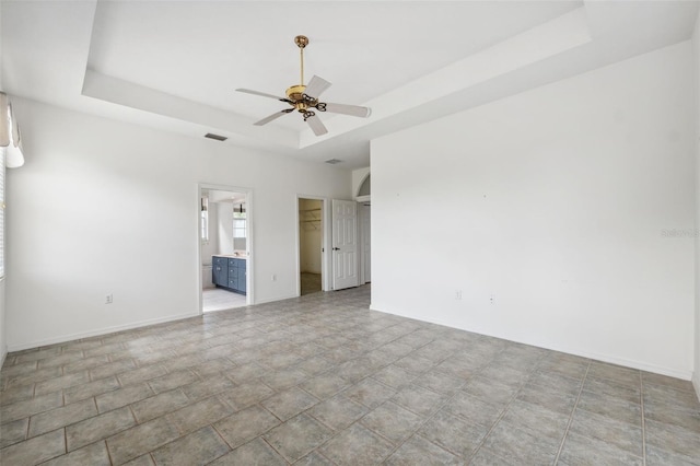 spare room with ceiling fan and a tray ceiling