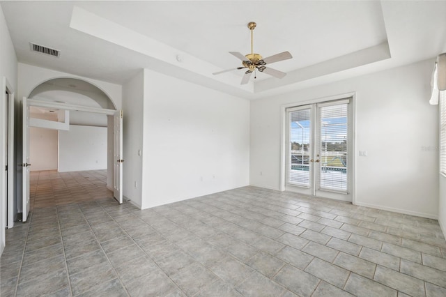 unfurnished room with french doors, ceiling fan, and a raised ceiling