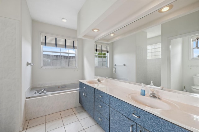 bathroom featuring toilet, vanity, tile patterned floors, and a relaxing tiled tub