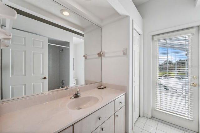 bathroom with vanity, tile patterned flooring, toilet, and tiled shower