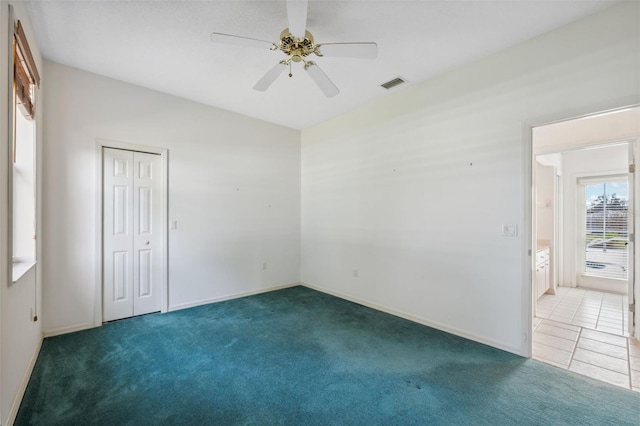 unfurnished room with ceiling fan and dark colored carpet