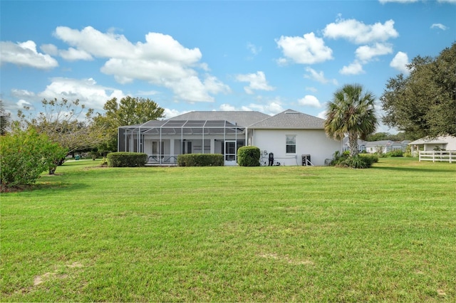 rear view of house with a yard and glass enclosure