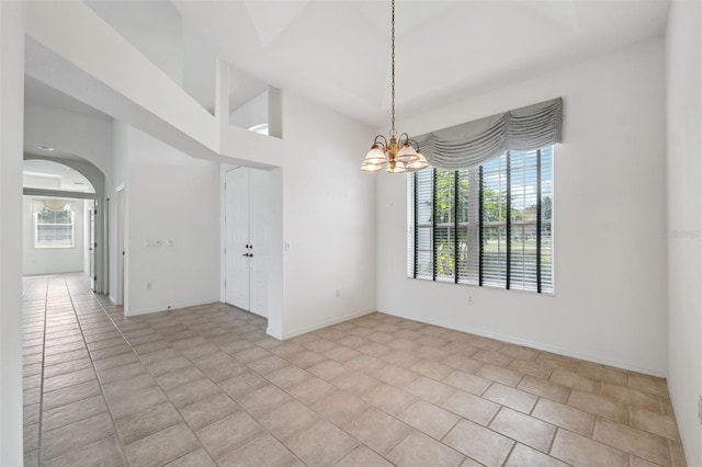 unfurnished room with a healthy amount of sunlight, light tile patterned floors, and a notable chandelier