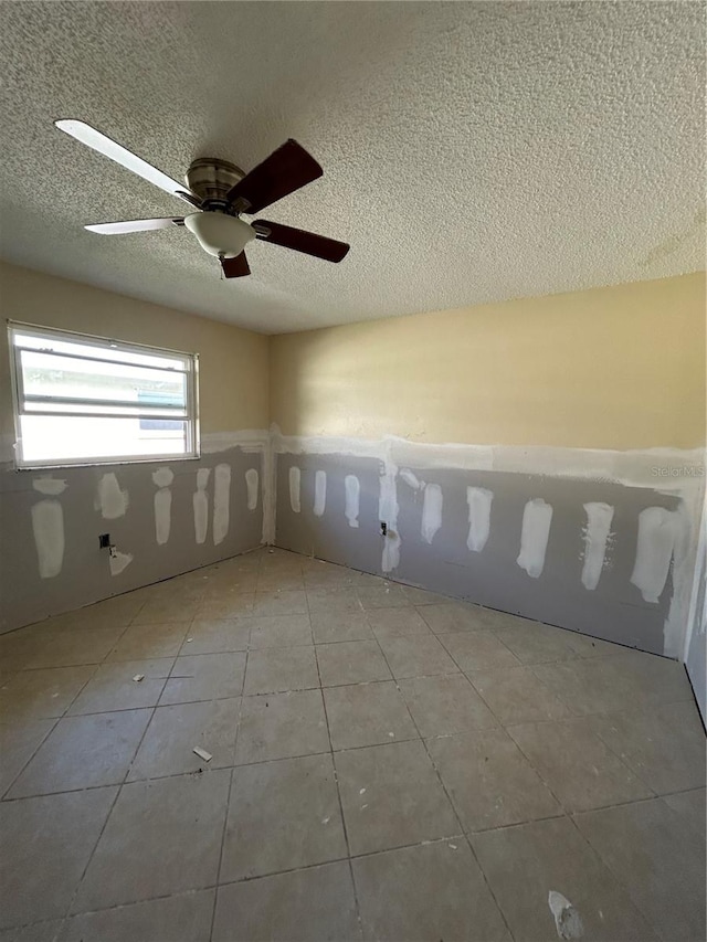 unfurnished room with ceiling fan, light tile patterned floors, and a textured ceiling