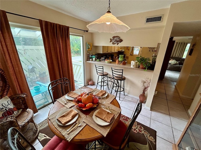 dining space featuring a healthy amount of sunlight, light tile patterned floors, and a textured ceiling