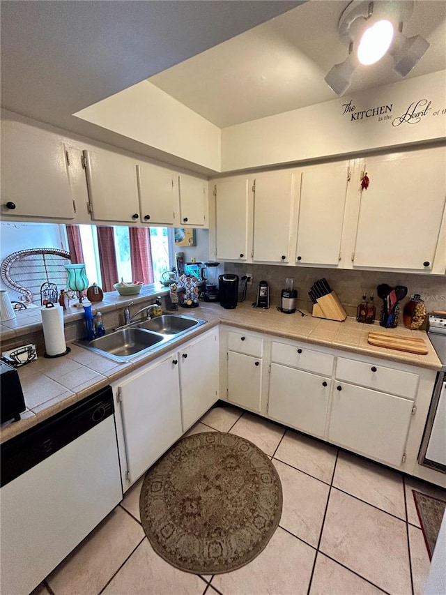 kitchen with tile countertops, dishwasher, white cabinets, sink, and light tile patterned flooring