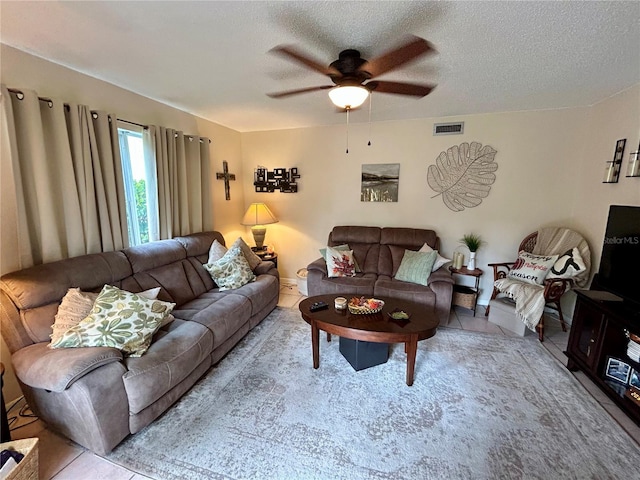 living room with a textured ceiling, ceiling fan, and light tile patterned floors