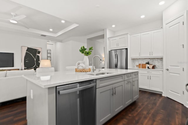 kitchen with stainless steel appliances, sink, dark hardwood / wood-style floors, backsplash, and an island with sink