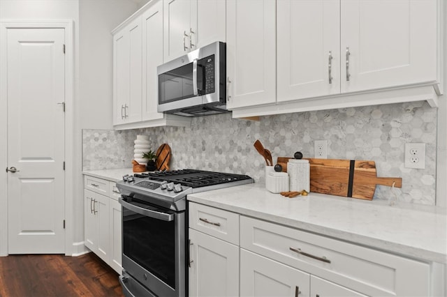 kitchen featuring white cabinetry, light stone counters, dark hardwood / wood-style floors, and stainless steel appliances