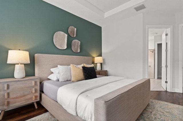 bedroom with connected bathroom and wood-type flooring