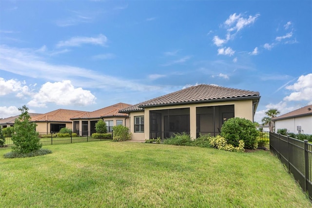 rear view of property featuring a sunroom and a lawn