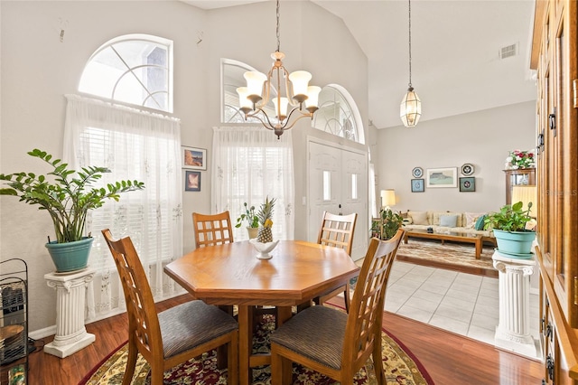 dining room with a chandelier, high vaulted ceiling, and light hardwood / wood-style flooring